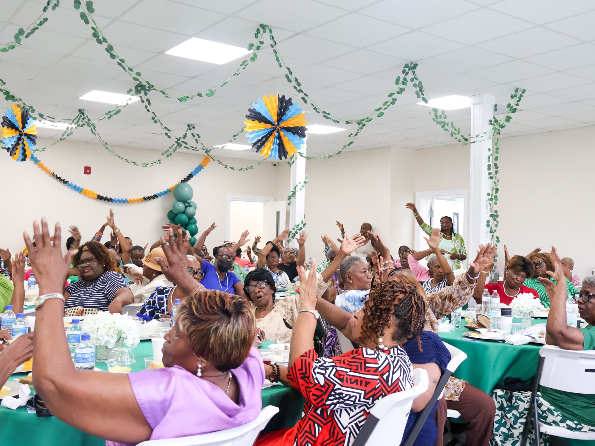 Congregation with hands raised during a church community breakfast in Nassau